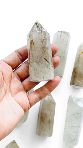 Hand holding a rutilated quartz crystal point