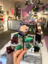 Leslie is holding a lepidolite crystal rose by the stem in the Ceremonial shop in Pittsburgh, PA