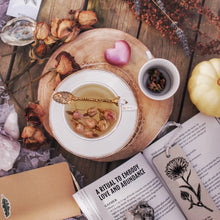 wooden table with magic flowers book open to a ritual to embody love and abundance 