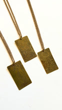 Brass necklace featuring an etched tarot card design, showcasing intricate artwork and a timeless finish