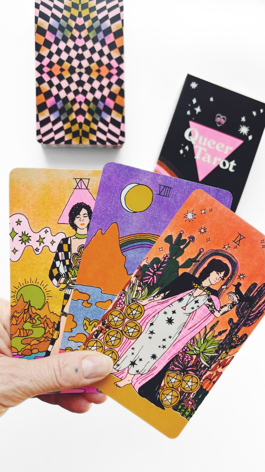 Hand holding three cards from the Queer Tarot